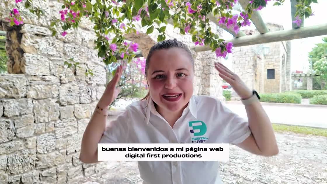 Mafer dando la bienvenida frente a un muro de piedra con buganvilias